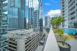 A high-rise building with a glass facade, a rooftop parking area, and a pool area with palm trees. - Stylish Brickell 1BR • Free Parking • Sleeps 6 (Miami)