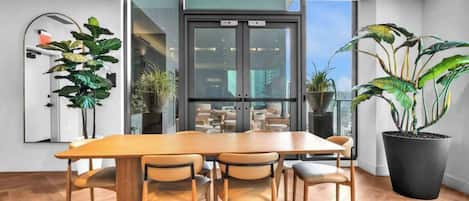 Een moderne vergaderruimte met een grote houten tafel, zes stoelen en potplanten.