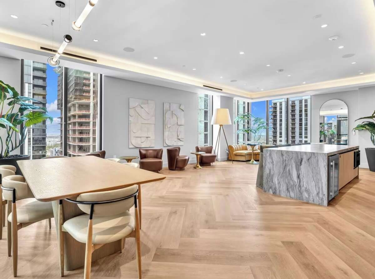 A spacious living area with a wooden herringbone floor, a marble island, and modern furniture.