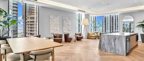 A spacious living area with a wooden herringbone floor, a marble island, and modern furniture.