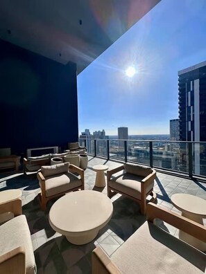 A rooftop terrace with outdoor seating, a clear view of the city skyline, and a modern building with a visible sign. - 501 Residences Lux 1BR - New Unit - Top Location! (Miami)