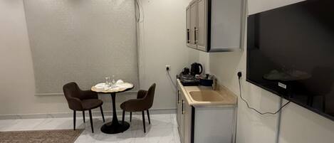 A compact living space with a dining area, kitchenette, and a mounted TV.