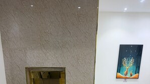 A lobby with a marble wall, a gold elevator, a blue sofa, and a clock on the wall. - asas rise (Riyadh)