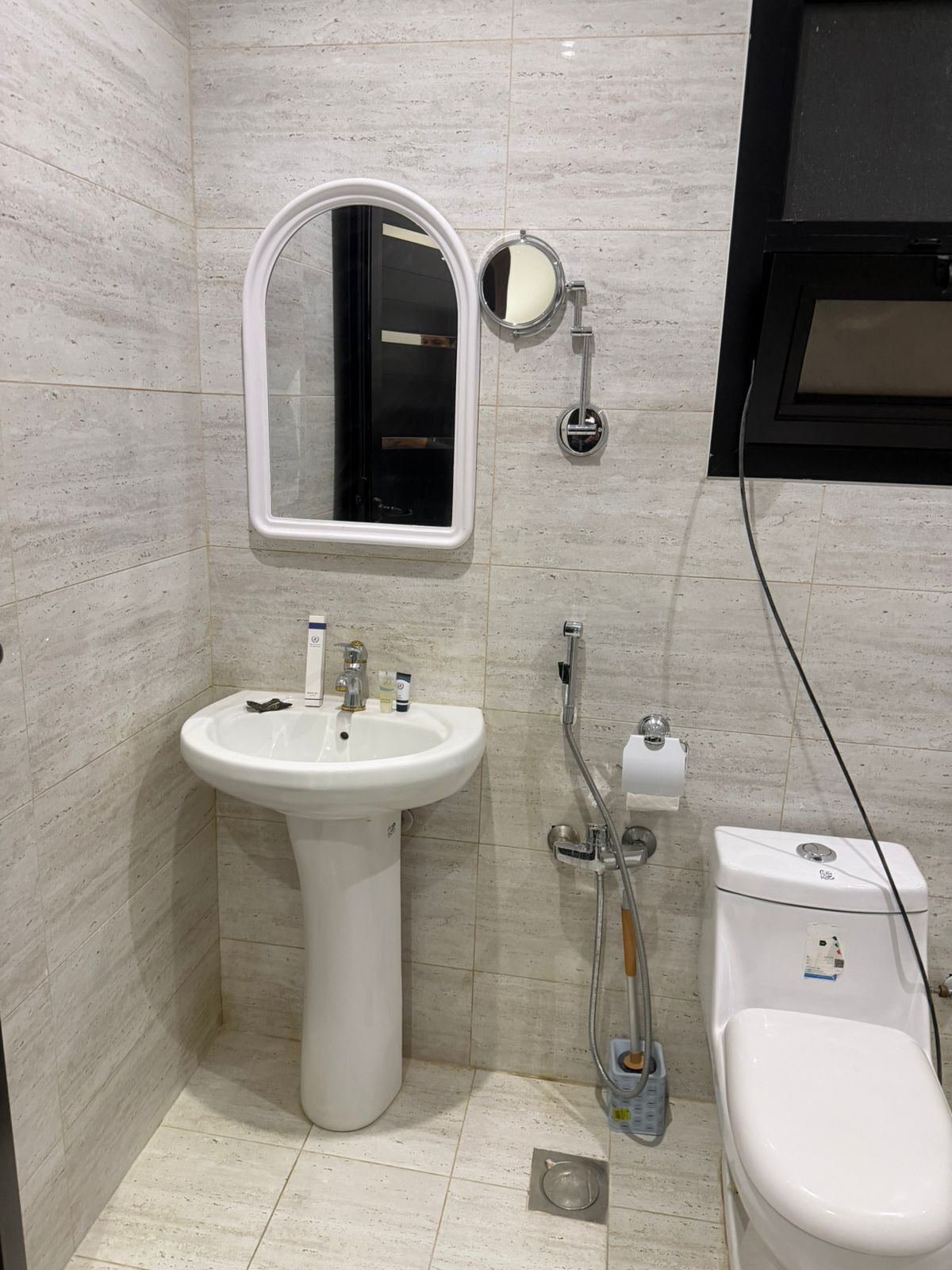 A bathroom with a pedestal sink, a mirror, a toilet, and a shower.