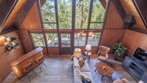 Un interior acogedor con techo de madera, un sofá, una mesa de centro, un televisor y un ventanal con vistas a una terraza.