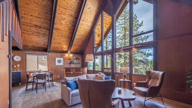 Una habitación amplia con techo alto, ventanas grandes, comedor y una zona de estar acogedora.