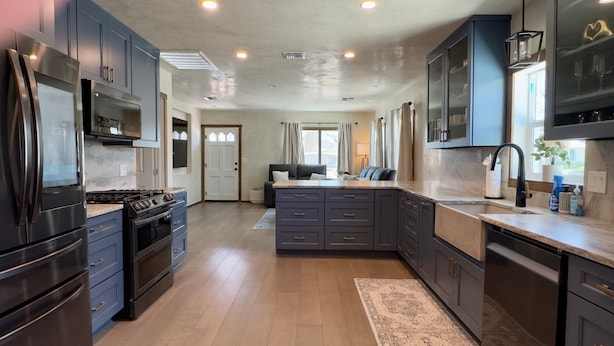A modern kitchen with dark cabinets, stainless steel appliances, and a central island. - Hackberry Haven | Pet-friendly | Great Yard (Fredericksburg)