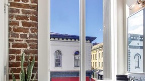 A modern bathroom with a large window, a potted plant, and a white vanity. - Contemporary 3BR Condo | Downtown Near Nightlife (Savannah)