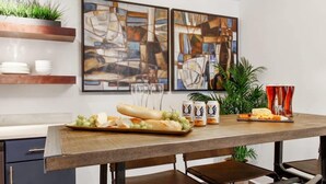 A dining area with a wooden table, plates, glasses, and a tray of food. - Contemporary 3BR Condo | Downtown Near Nightlife (Savannah)