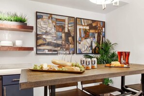 A dining area with a wooden table, plates, glasses, and a tray of food. - Contemporary 3BR Condo | Downtown Near Nightlife (Savannah)