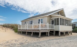 A beachfront house with a wooden deck, a covered porch, and a sandy beach in the background. - Aqua Hol - S Nags Head MP 18, Oceanfront, Ocean View, 3 Bedrooms, Flex Stays, Pets OK (South Nags Head)