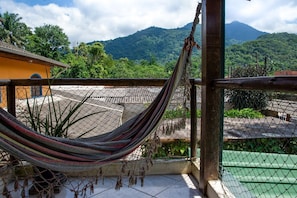 A hammock on a balcony with a view of mountains and greenery. - Casa com 2 suítes e Churrasqueira no Figueira (Ubatuba)