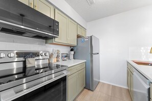 A modern kitchen with stainless steel appliances, light-colored cabinets, and a tiled backsplash. - Renovated Condo near Silver Dollar City w Table Rock Lake View_Free Attraction Tickets_Private Deck (Branson)