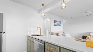 Una cocina moderna con encimera blanca, electrodomésticos de acero inoxidable y detalles dorados.