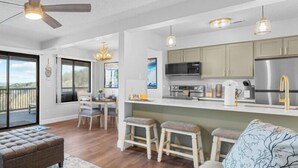Una cocina moderna con una isla central, taburetes de bar y un comedor con vistas.