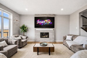 A modern living room with a fireplace, a flat-screen TV, and two sofas.