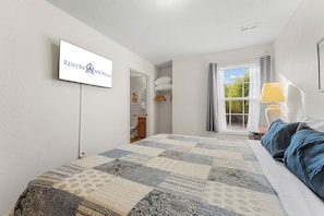 A bedroom with a bed, a window with curtains, a bedside table with a lamp, and a wall-mounted TV displaying RENTTBROWNSON.COM. - Near Table Rock Lake & Sdc_Daily Free Tickets_Seasonal Cmty Pool/Hot Tub_Peaceful Deck (Branson)