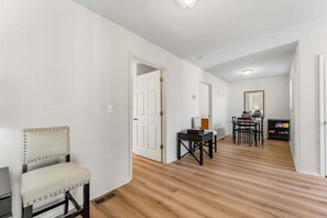A hallway with a chair, a table, and a door leading to another room. - Near Table Rock Lake & Sdc_Daily Free Tickets_Seasonal Cmty Pool/Hot Tub_Peaceful Deck (Branson)