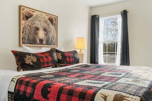 A bed with a quilt, a lamp, a window with curtains, and a bear picture on the wall. - Near Table Rock Lake & Sdc_Daily Free Tickets_Seasonal Cmty Pool/Hot Tub_Peaceful Deck (Branson)