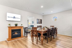 A dining room with a fireplace, a dining table set for six, and a television mounted on the wall. - Near Table Rock Lake & Sdc_Daily Free Tickets_Seasonal Cmty Pool/Hot Tub_Peaceful Deck (Branson)