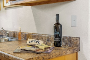 Un comptoir de cuisine avec une bouteille de vin, un verre et quelques magazines.