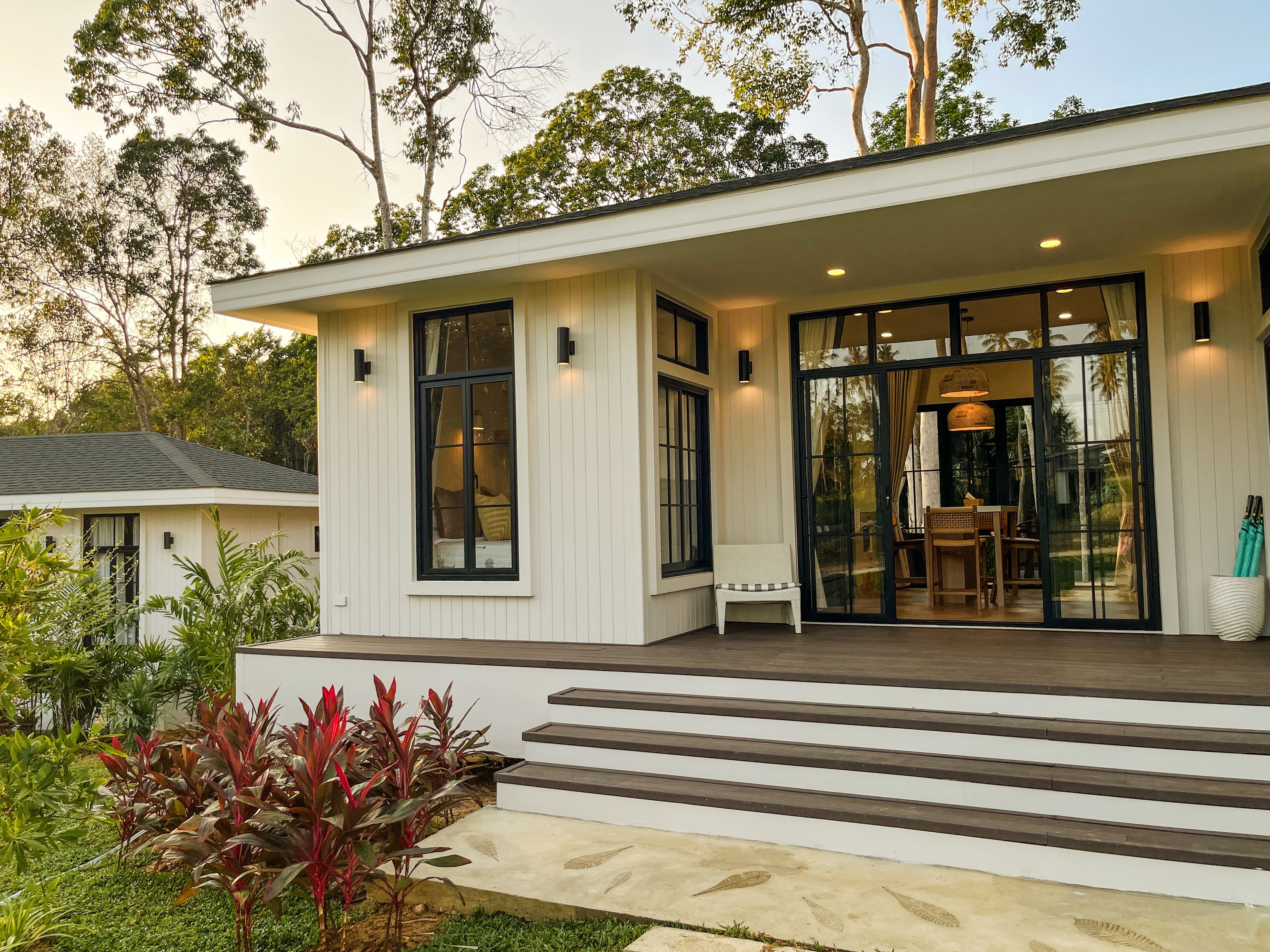 A modern house with a covered porch, large windows, and a staircase leading to the entrance.
