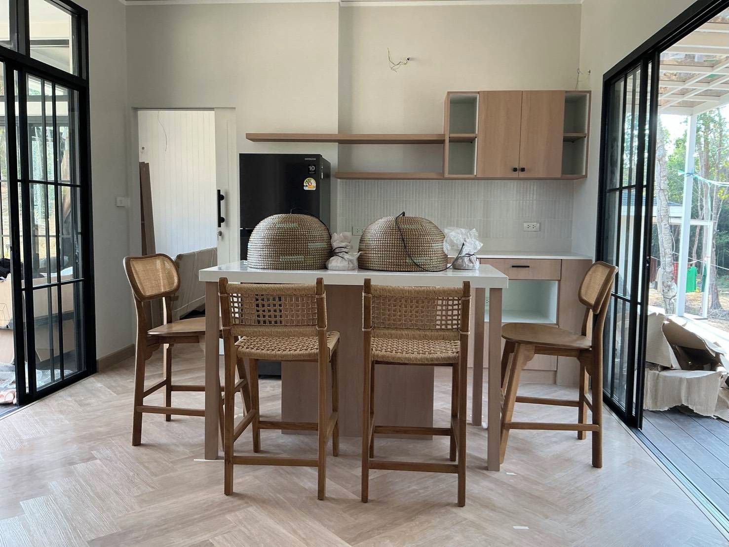 Een moderne keuken met een eethoek, met een groot raam, een koelkast en een houten eettafel met stoelen.