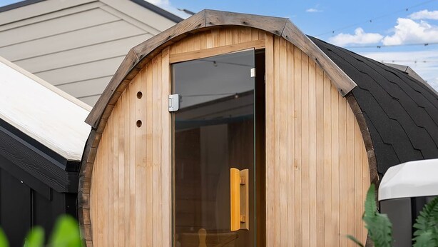 A wooden barrel-shaped structure with a sliding glass door, surrounded by greenery and a clear sky. - Aloha Nashville🤙🏻~ Private Sauna & Hot Tub | Rooftop Oasis | City Views | Close to Broadway! (Nashville)