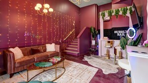 A modern interior with a sofa, coffee table, staircase, and a bar area. - Aloha Nashville🤙🏻~ Private Sauna & Hot Tub | Rooftop Oasis | City Views | Close to Broadway! (Nashville)
