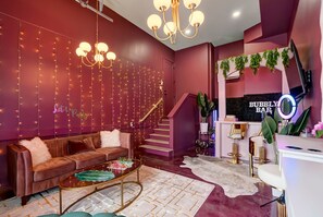 A modern interior with a sofa, coffee table, staircase, and a bar area. - Aloha Nashville🤙🏻~ Private Sauna & Hot Tub | Rooftop Oasis | City Views | Close to Broadway! (Nashville)