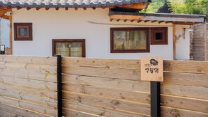 Et traditionelt koreansk hus med tegltag, trævægge og et skilt.