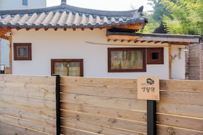 Una casa tradicional coreana con techo de tejas, paredes de madera y un letrero.
