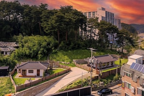 A residential area with traditional and modern buildings, a paved pathway, and a car parked on the street. - Gangneung Orabdori Hanok Pension (Gangneung)