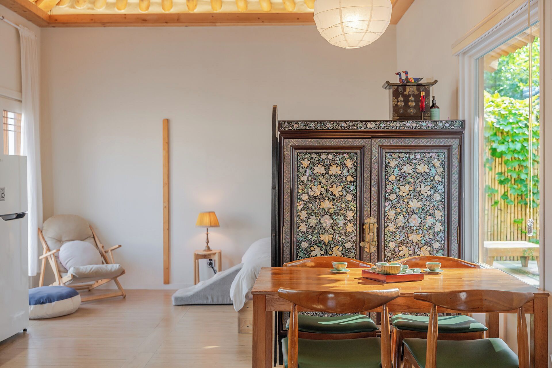 Comedor con mesa y sillas de madera, un aparador decorativo con detalles intrincados, y vista a zonas verdes exteriores.