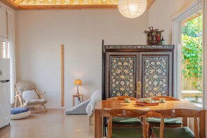Een eetruimte met een houten tafel en stoelen, een decor kast met gedetailleerde versieringen, en uitzicht op groen buiten.