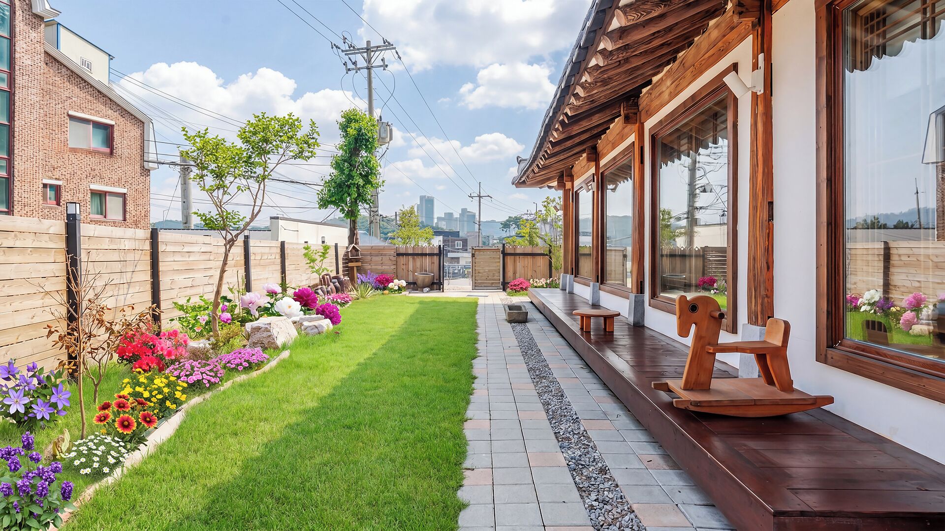 Una propiedad residencial con un césped bien cuidado, una terraza de madera con asientos y vistas a la ciudad.