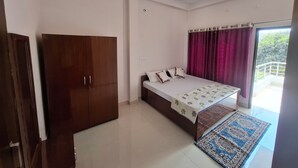 A bedroom with a bed, wardrobe, ceiling fan, and a view to the outside.