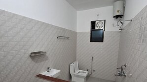 A bathroom with a toilet, sink, shower, and a small window.