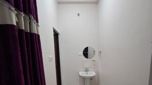 A narrow hallway with a white sink and a mirror on the wall.