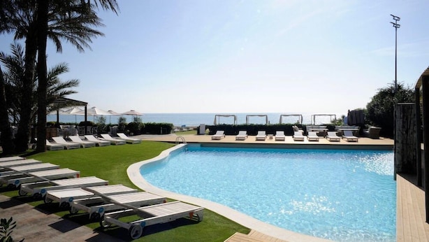 Ein Pool mit Liegestühlen, eine Rasenfläche und Meerblick.