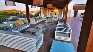 Eine Terrasse im Freien mit weißen Möbeln, darunter Sofas und Stühle, unter einer Holz-Pergola.
