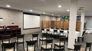 Ein Konferenzraum mit Projektorleinwand, Holzschränken und einer Bestuhlung für Teilnehmer.