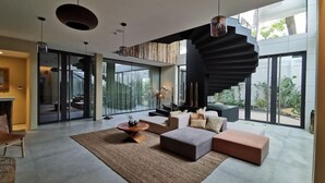 Ein modernes Wohnzimmer mit einer Wendeltreppe, großen Fenstern und minimalistischem Design.