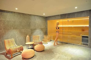 Ein Wellnessraum mit Massagetisch, Korbsesseln und einem großen Spiegel.