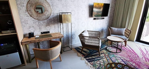 Ein modernes Zimmer mit Schreibtisch aus Holz, Korbstühlen, einem Flachbildfernseher und einem großen Fenster.