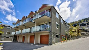 Un edificio de varios pisos con balcones, garaje y fachada de piedra.