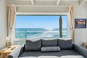 A room with a large window, a sofa, a lamp, and a remote control. - Pacific Edge Retreat | Entire Estate, Ocean Views, Luxury Coastal Escape (Oceanside)