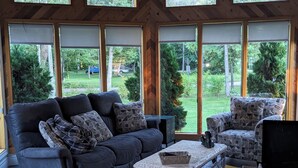 A room with a dark-colored sofa, a patterned armchair, a small table, and a computer desk with a monitor and keyboard. - Sunset spectacular with resort amenities (Kawartha Lakes)