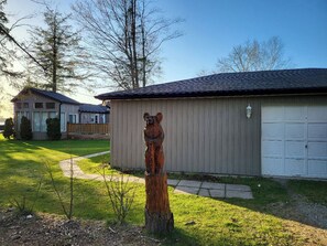 Ein Wohngebiet mit Garage, einer Holzskulptur und einem Haus mit Satteldach.