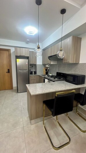 Una cocina moderna con una isla central, electrodomésticos de acero inoxidable e iluminación colgante.
